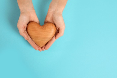 Woman holding decorative heart on color background, top view with space for text