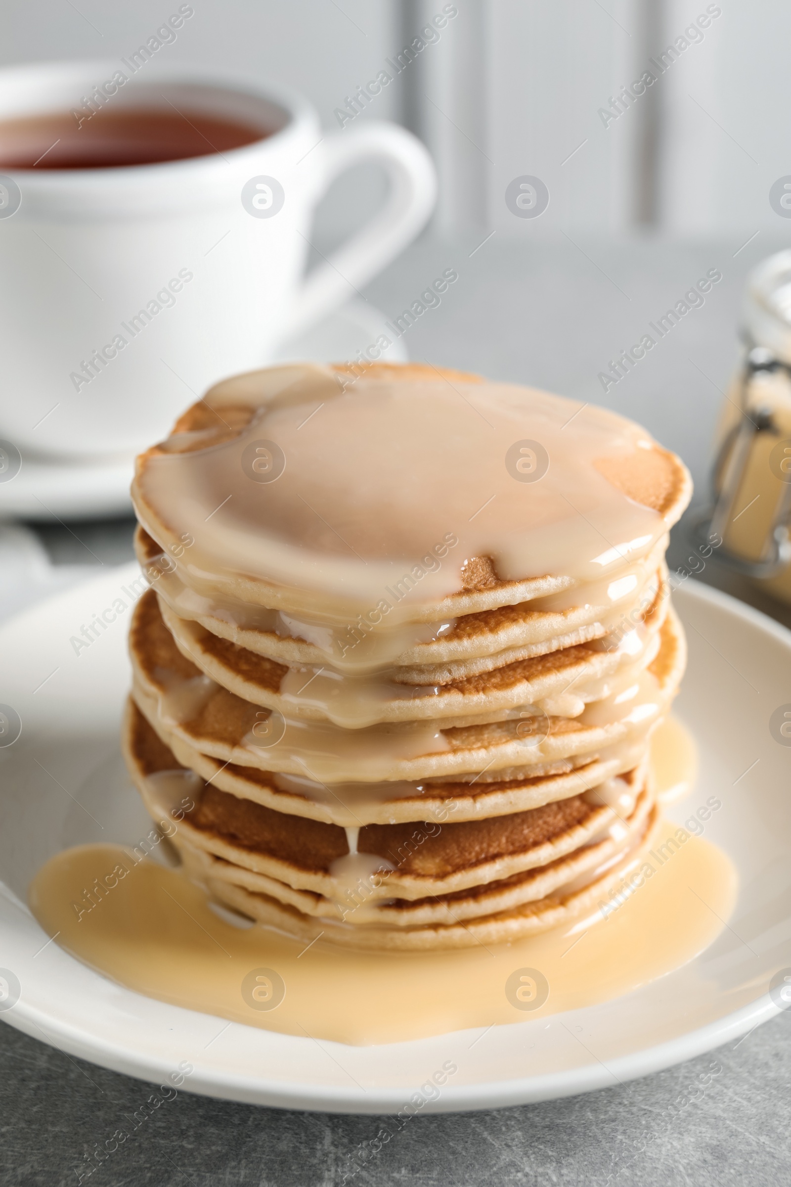 Photo of Plate with pancakes and condensed milk served on table. Dairy product