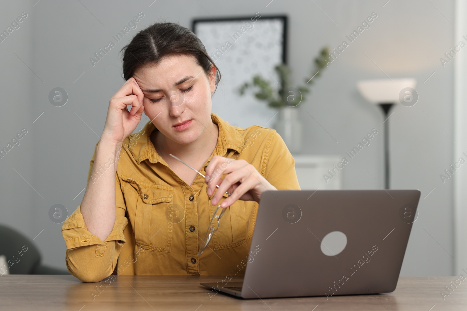 Photo of Overwhelmed woman sitting with laptop at table indoors