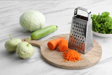 Photo of Grater and fresh vegetables on white marble table
