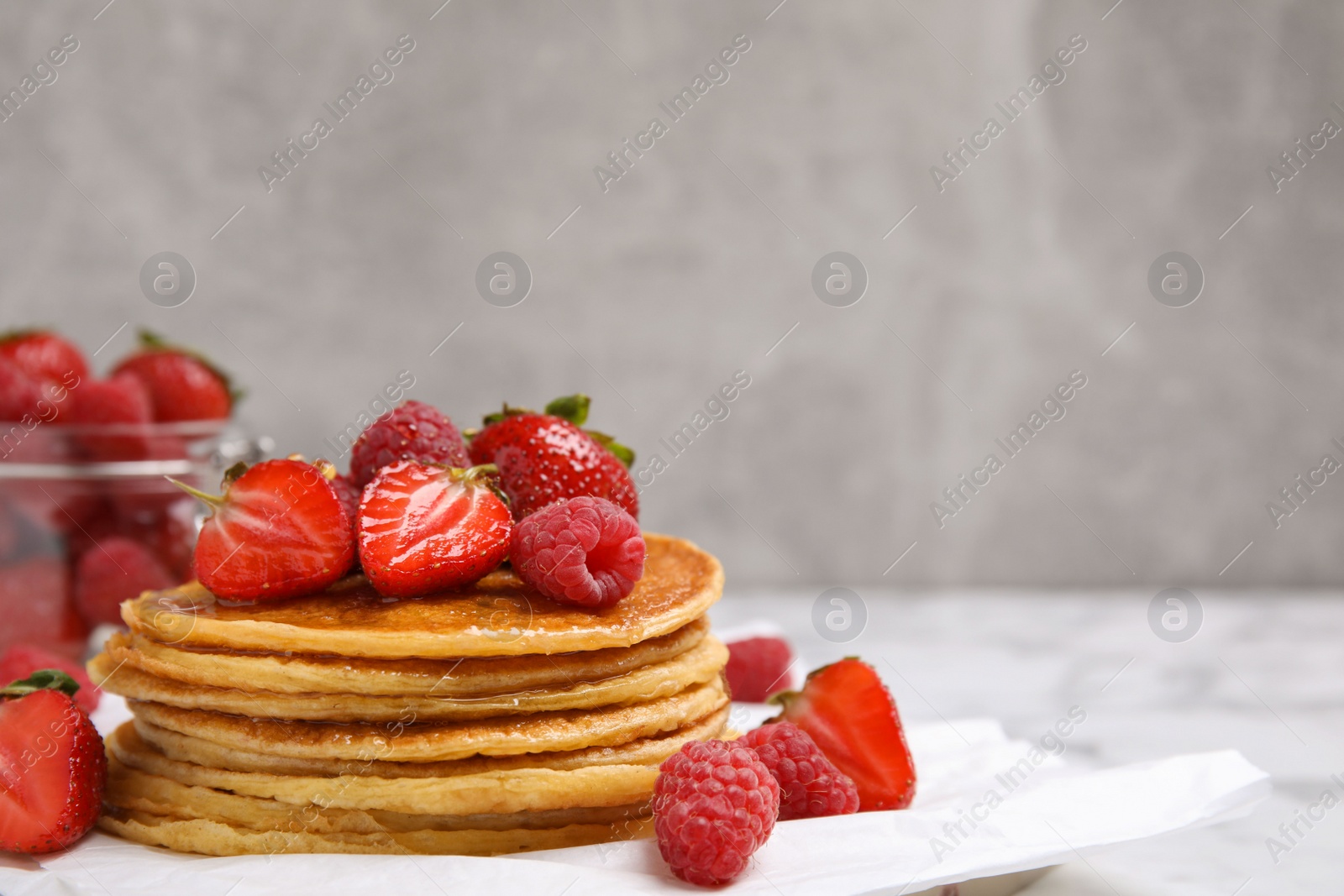 Photo of Tasty pancakes with fresh berries and honey on table, closeup. Space for text