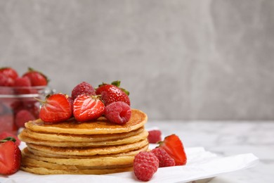 Tasty pancakes with fresh berries and honey on table, closeup. Space for text