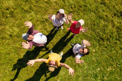 Top aerial view of happy people standing in circle on green grass. Drone photography