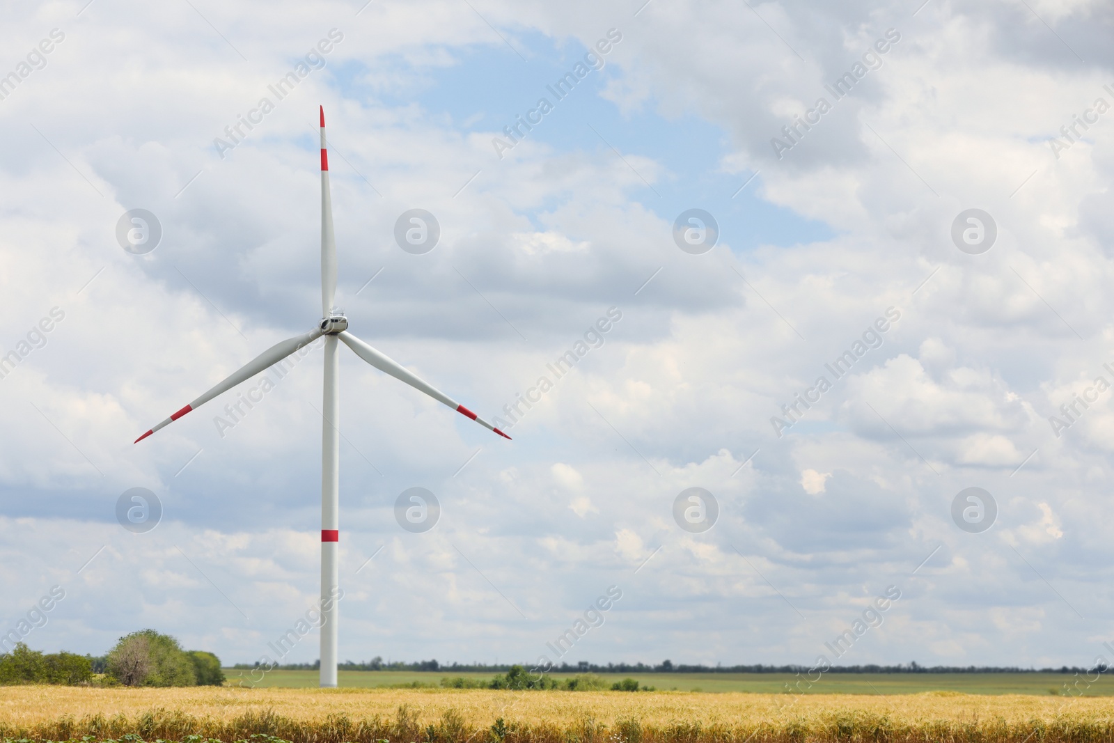 Photo of Modern wind turbine in field on cloudy day. Alternative energy source