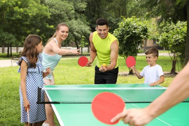 Happy family playing ping pong in park