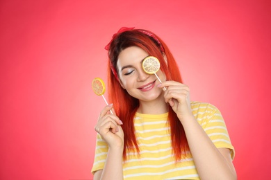 Photo of Young woman with bright dyed hair holding lollipops on red background