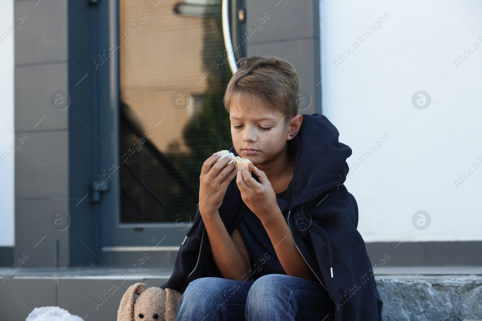 Photo of Poor little boy with bread on city street
