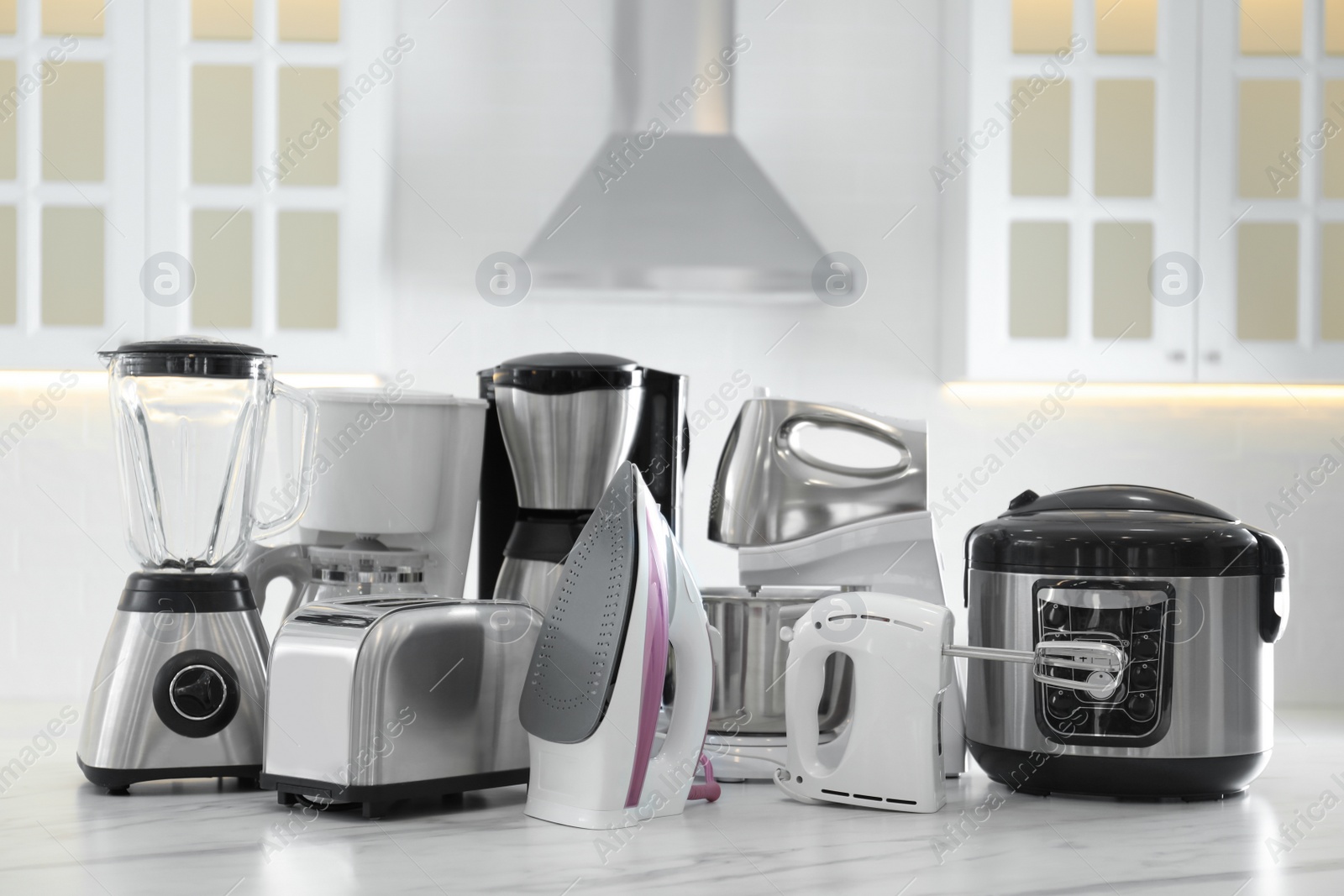 Photo of Set of modern home appliances on white marble table in kitchen