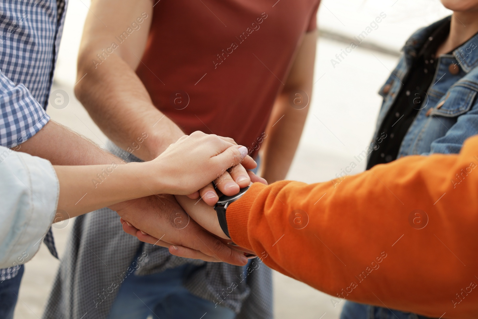 Photo of Group of people holding hands together outdoors, closeup