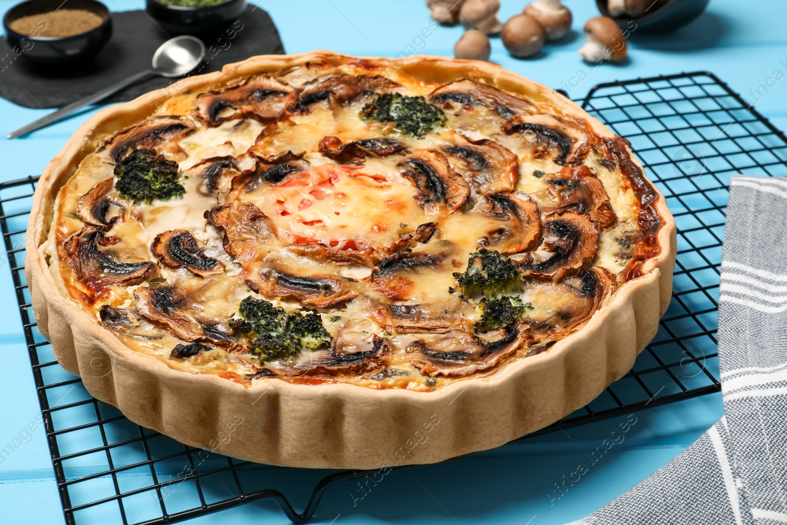 Photo of Delicious quiche with mushrooms on light blue wooden table, closeup