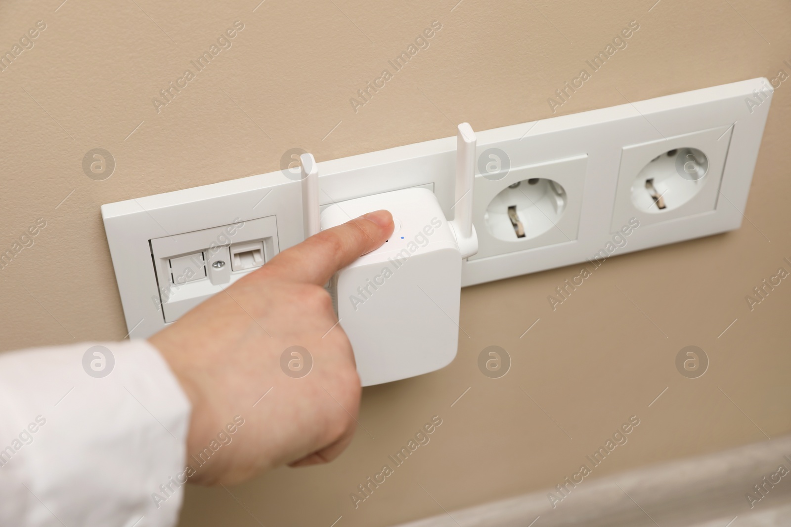 Photo of Woman turning on wireless Wi-Fi repeater indoors, closeup