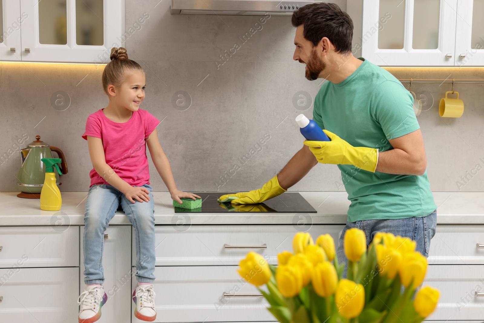 Photo of Spring cleaning. Father and daughter tidying up stove in kitchen together