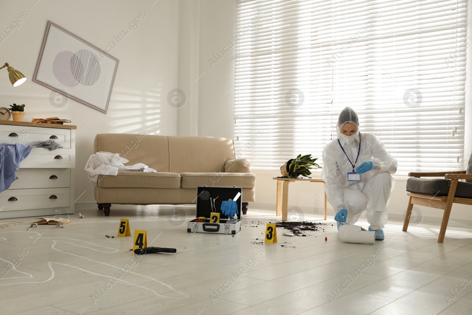 Photo of Investigator in protective suit working at crime scene indoors