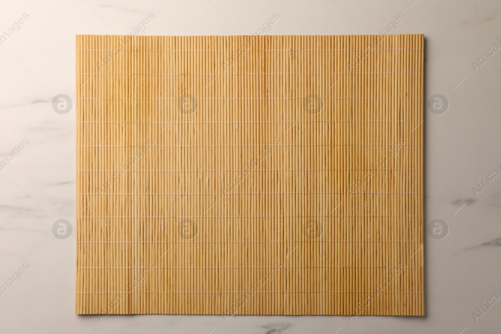 Photo of Bamboo mat on white marble table, top view. Space for text