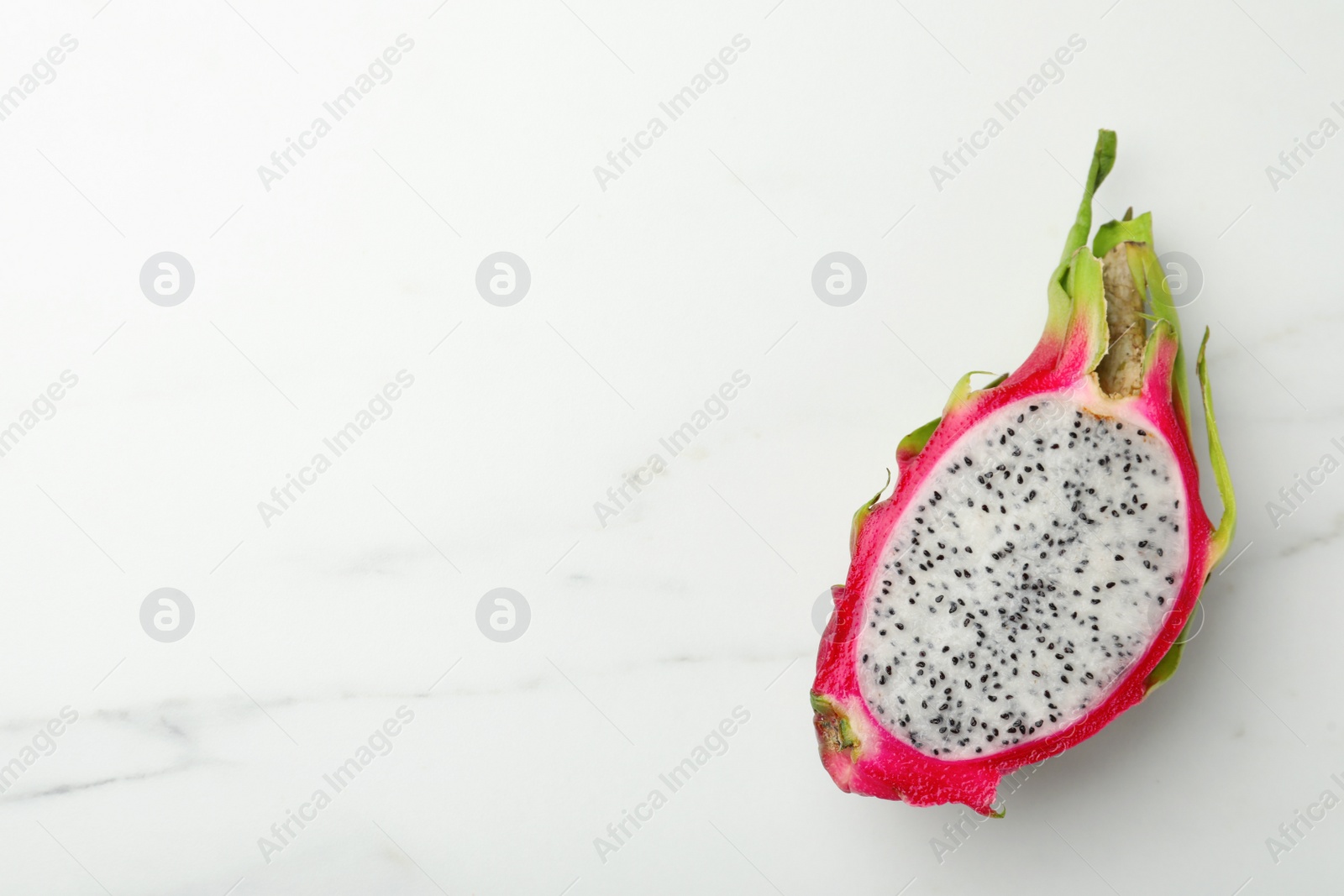 Photo of Half of delicious dragon fruit on white marble table, top view. Space for text