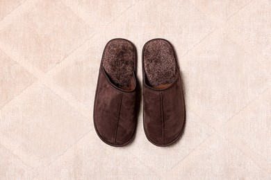 Photo of Brown slippers on soft carpet, top view