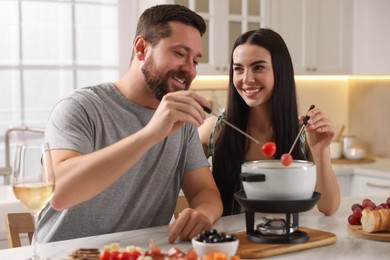 Affectionate couple enjoying fondue during romantic date in kitchen