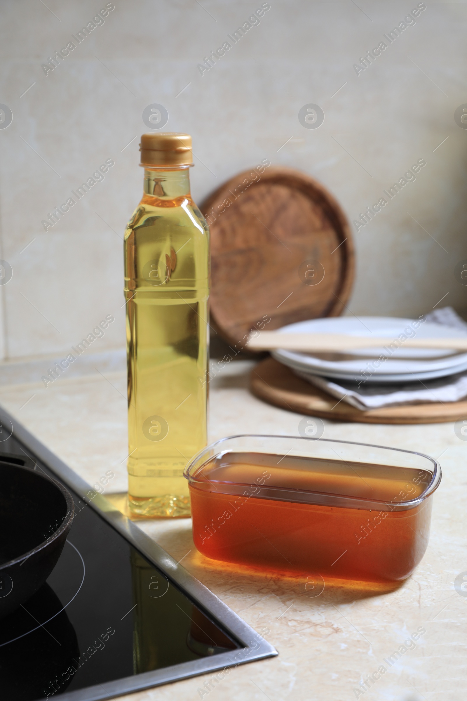 Photo of New and used cooking oil near stove on kitchen counter