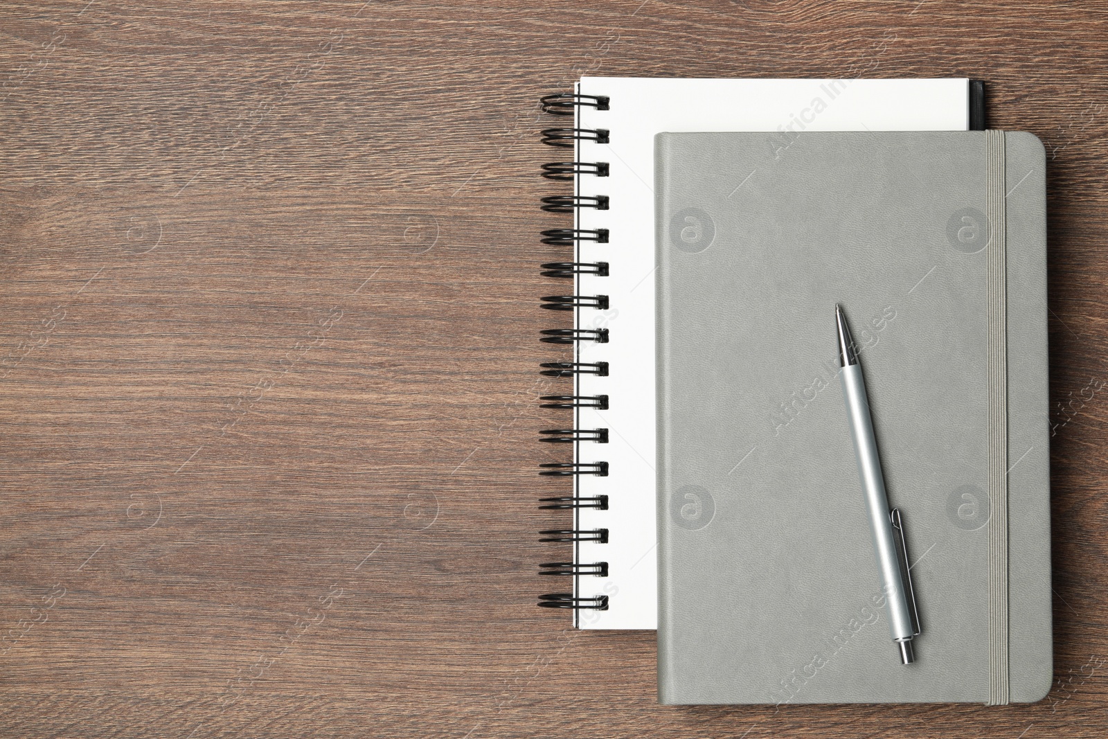 Photo of Stylish notebooks and pen on wooden table, top view. Space for text