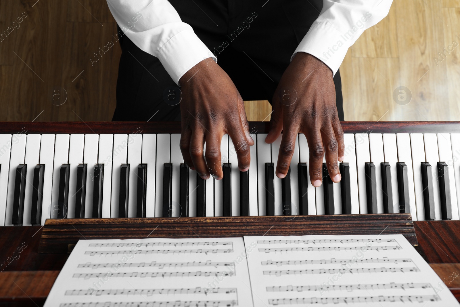 Photo of African-American man playing piano indoors, above view. Talented musician