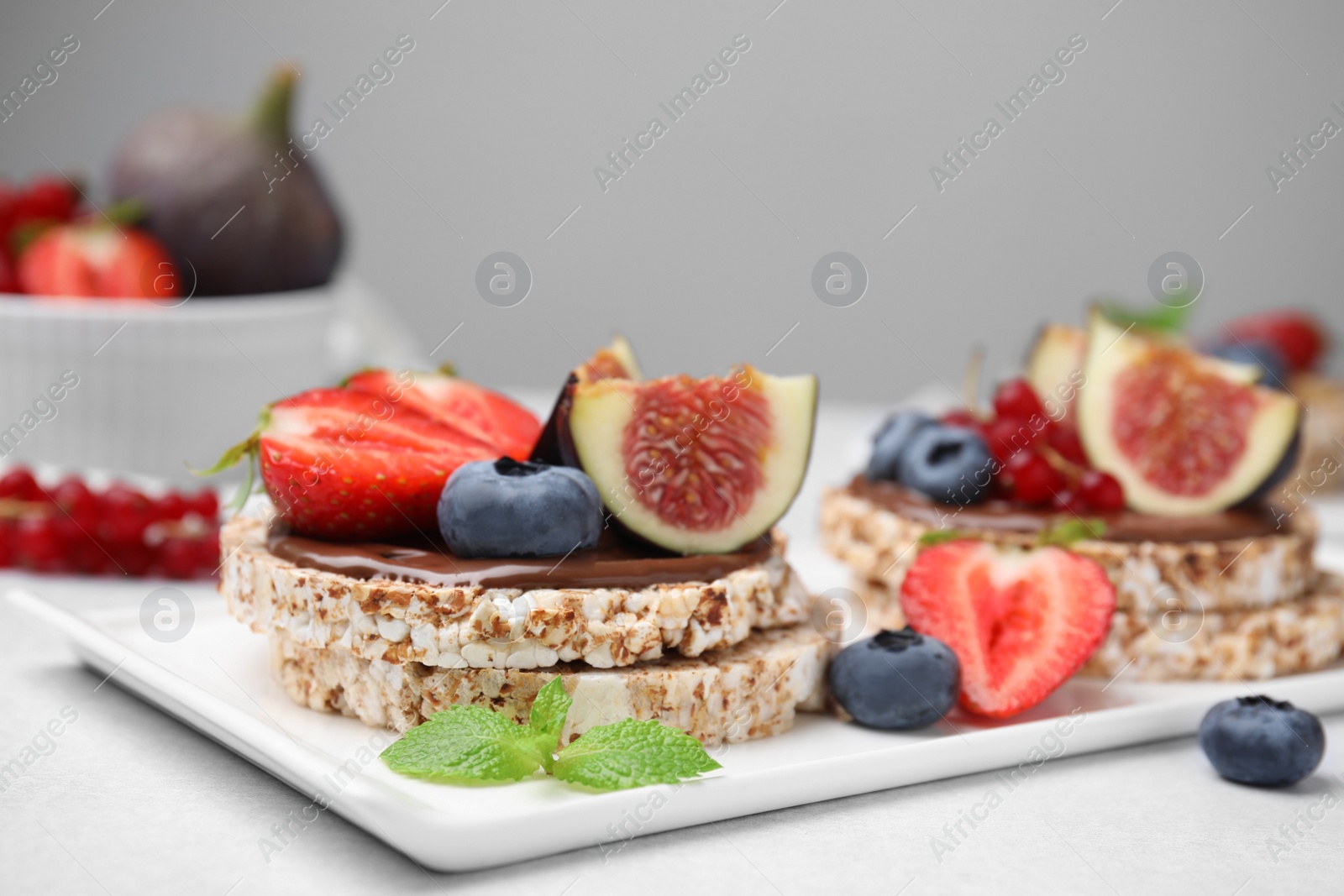 Photo of Tasty crispbreads with chocolate, figs and berries served on light table