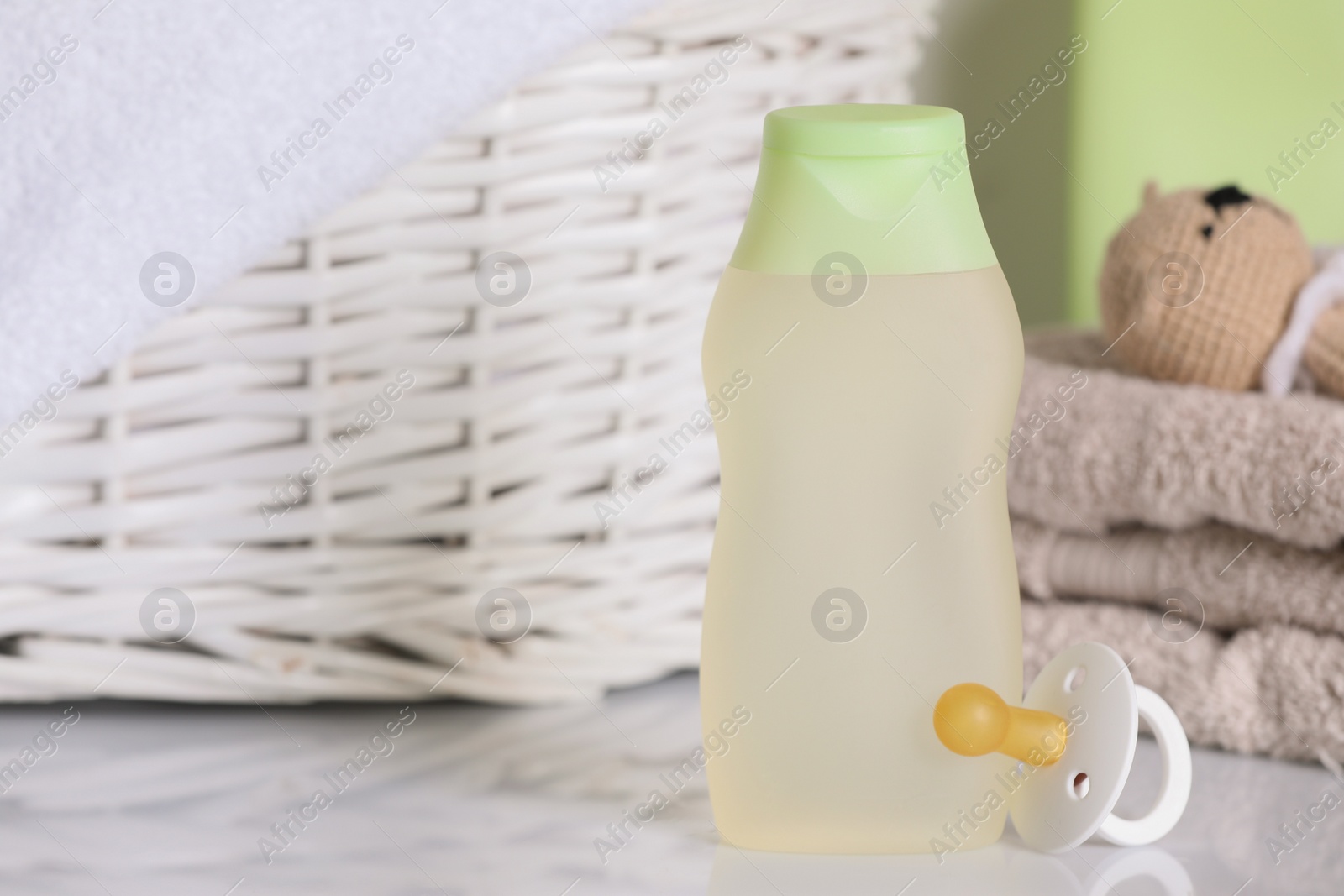 Photo of Bottle of baby cosmetic product and pacifier near accessories on white table. Space for text