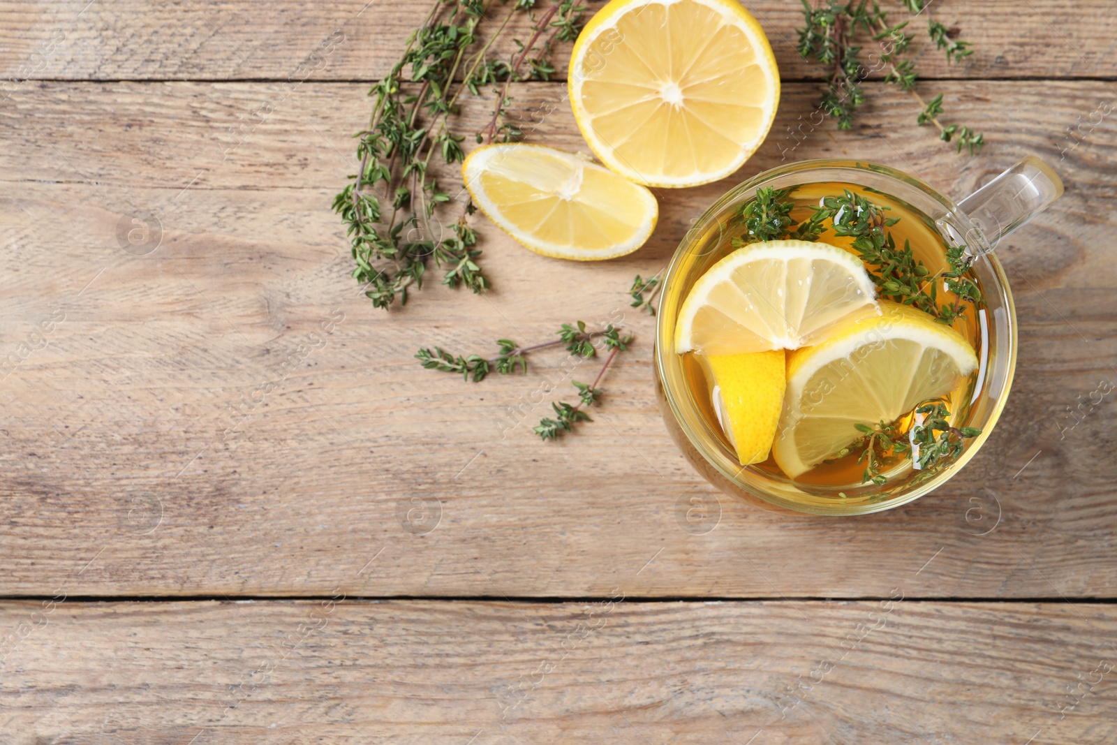 Photo of Aromatic herbal tea with thyme and lemon on wooden table, flat lay. Space for text