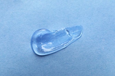 Photo of Sample of transparent gel on light blue background, closeup