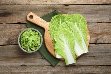 Photo of Cut fresh Chinese cabbage and leaves on wooden table, top view