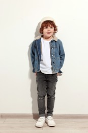 Photo of Fashion concept. Stylish boy posing near white wall