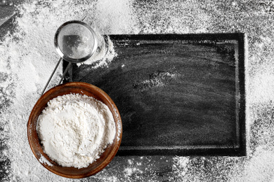 Photo of Frame made with flour near kitchenware on black table, flat lay. Space for text