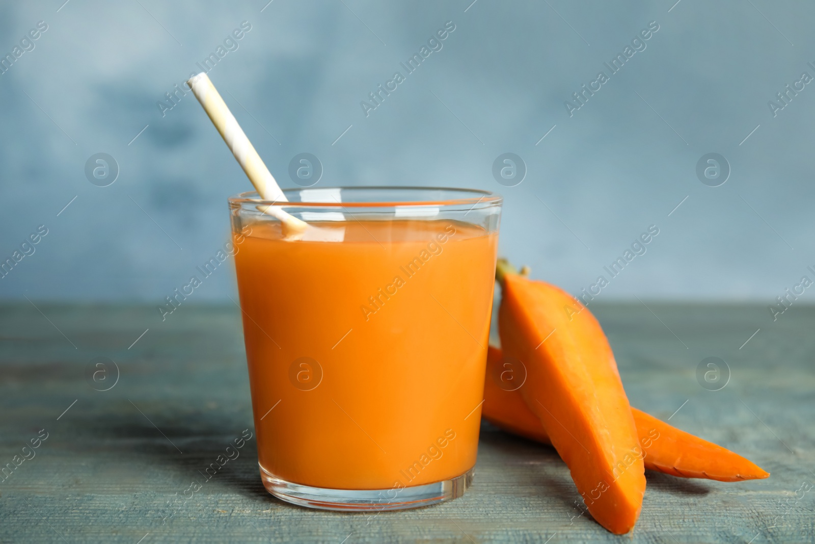 Photo of Freshly made carrot juice in glass on wooden table