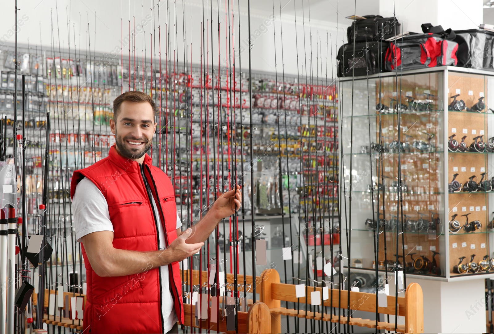 Photo of Salesman with fishing rods in sports shop. Space for text