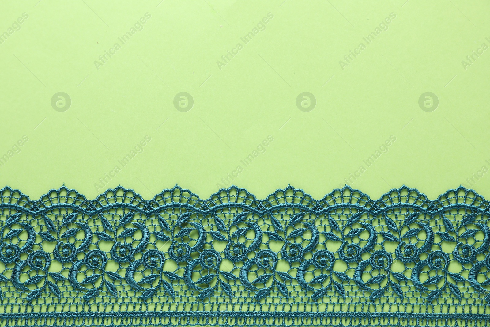 Photo of Beautiful lace on green background, top view. Space for text