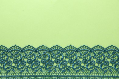 Beautiful lace on green background, top view. Space for text