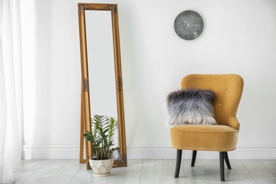 Photo of Armchair with pillow near white wall in room