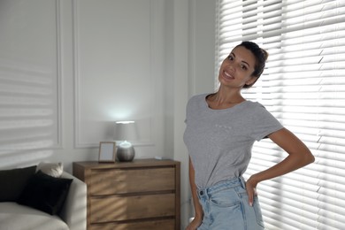 Portrait of beautiful woman near window at home, space for text