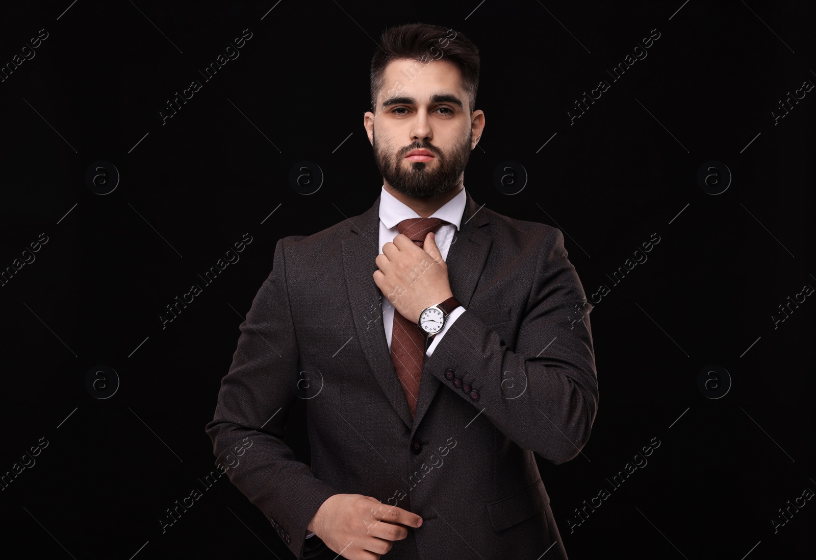 Photo of Handsome businessman in suit and necktie on black background