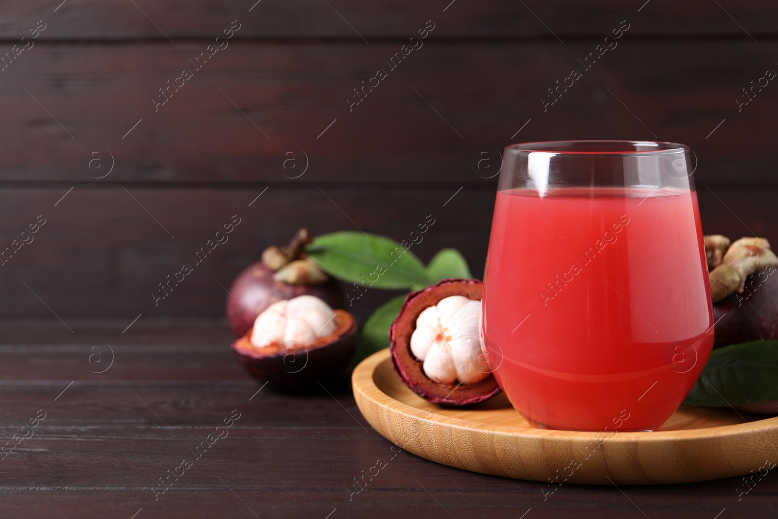 Photo of Delicious mangosteen juice in glass on wooden table. Space for text