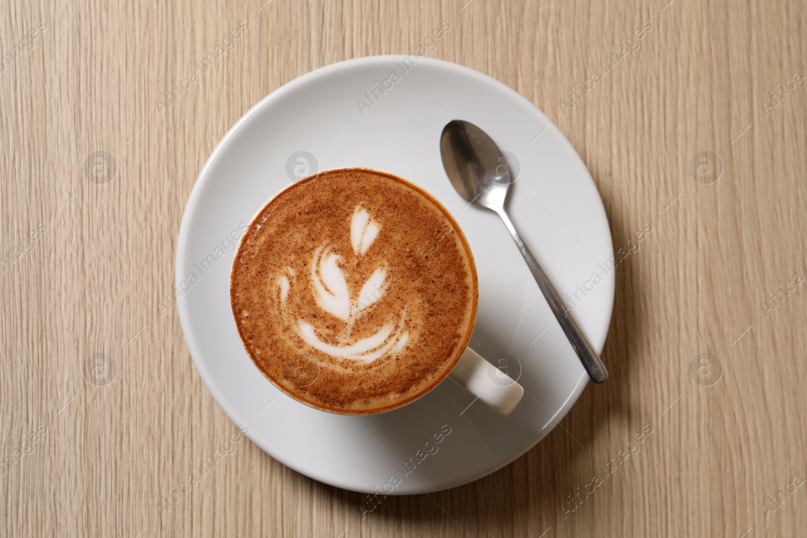 Photo of Cup of aromatic coffee and spoon on wooden table, top view