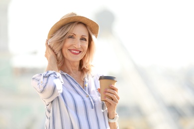 Beautiful mature woman with cup of coffee outdoors