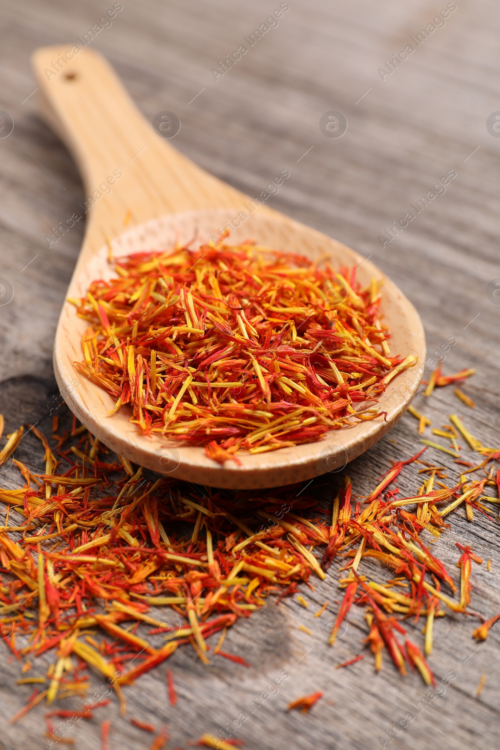 Photo of Aromatic saffron and spoon on wooden table, closeup