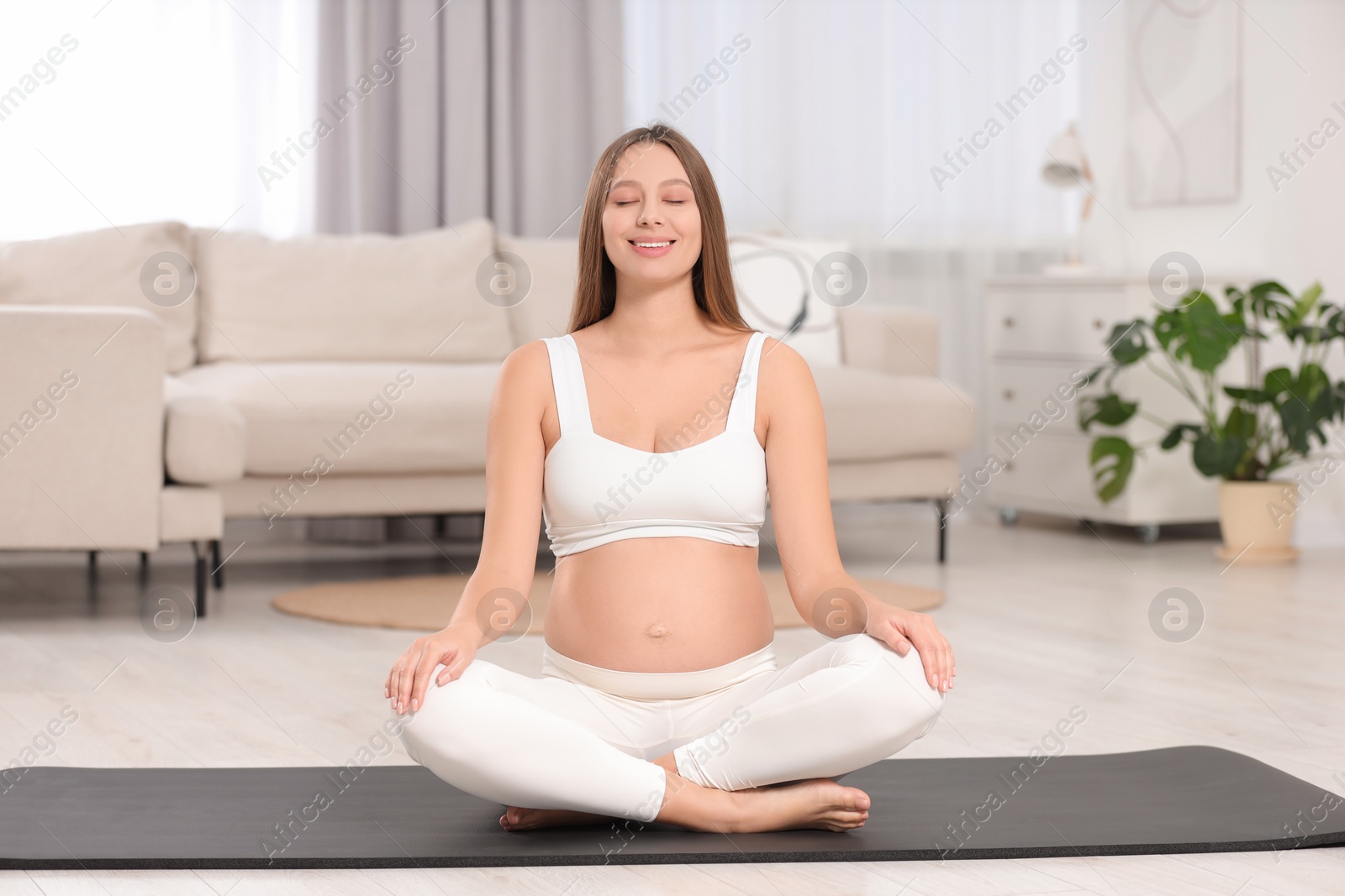 Photo of Pregnant woman meditating on yoga mat at home