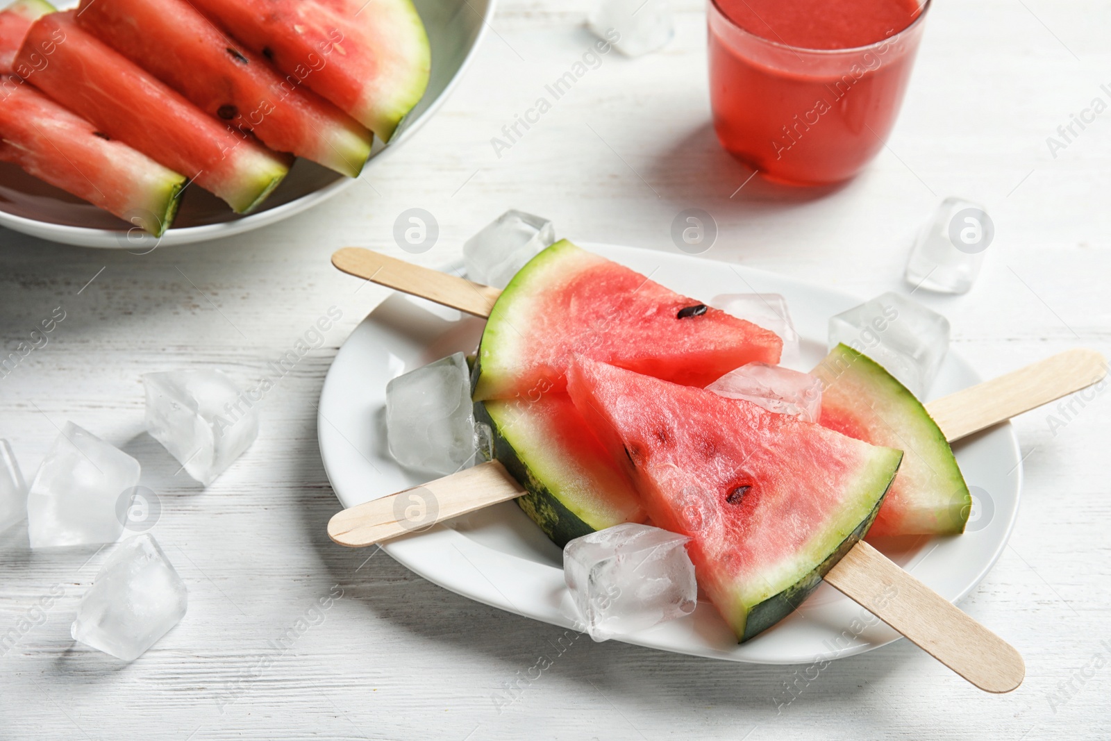 Photo of Plate with watermelon popsicles and ice cubes on table