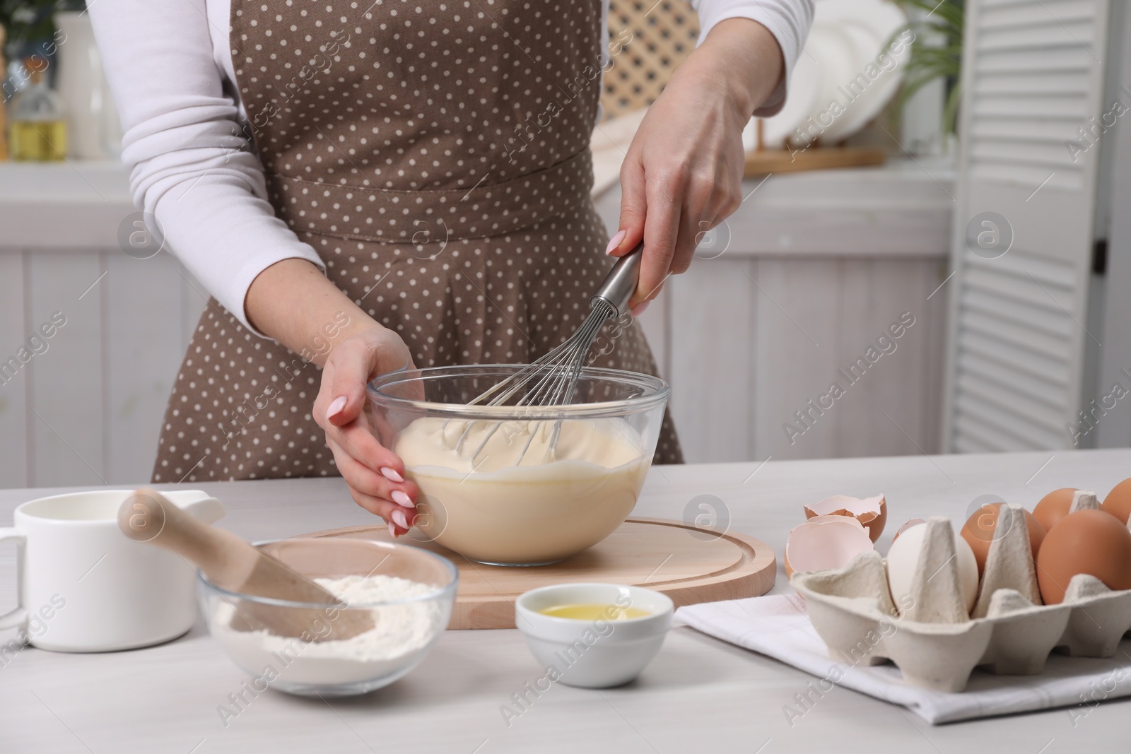 Photo of Woman making dough with whisk in bowl at table, closeup