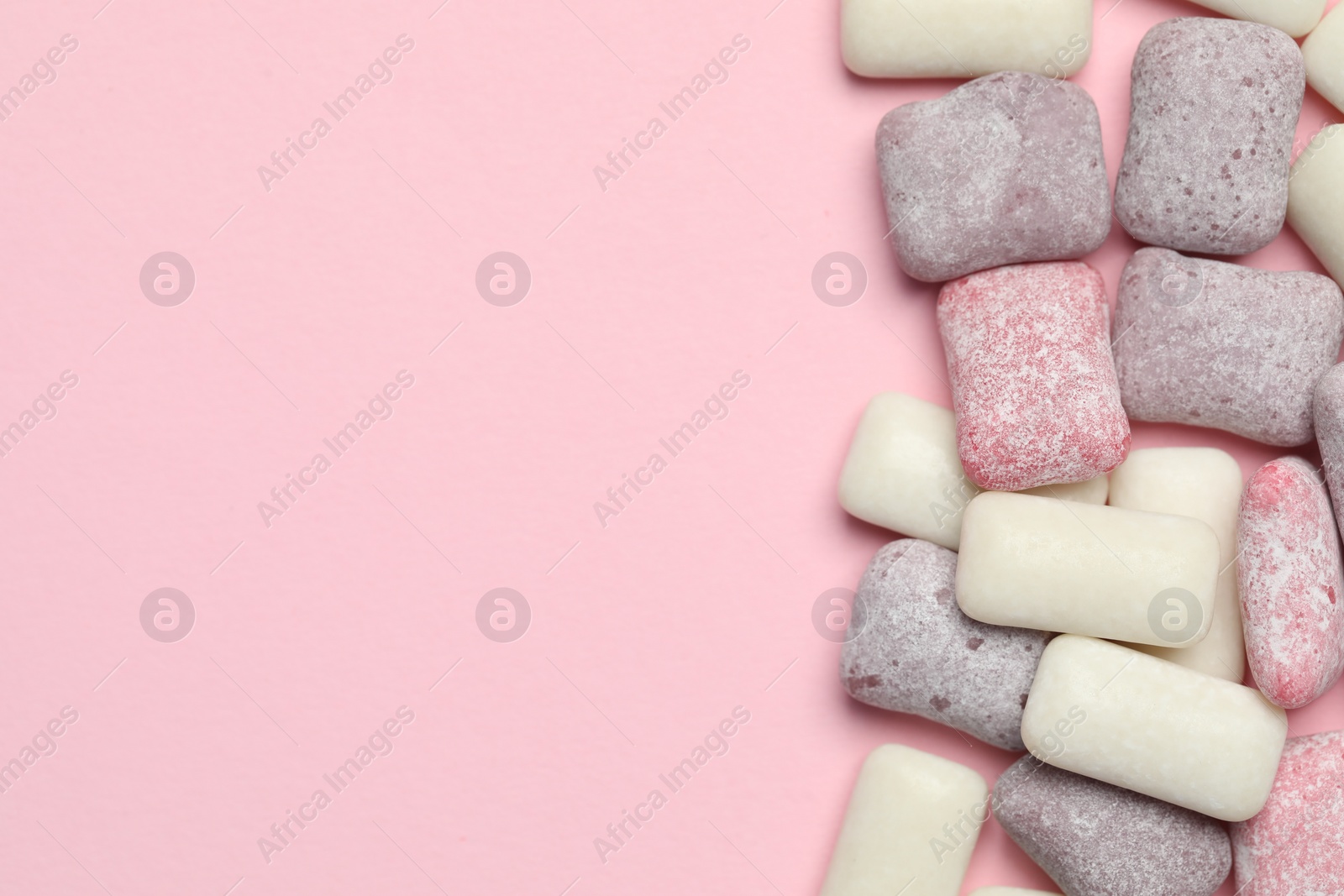 Photo of Different tasty colorful bubble gums on pink background, flat lay. Space for text