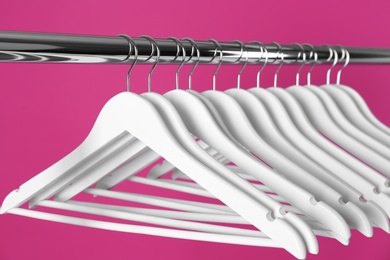 Metal rack with clothes hangers on color background, closeup