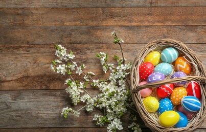 Photo of Flat lay composition with painted Easter eggs and blossoming branches on wooden background