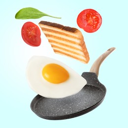 Image of Tasty fried chicken egg, tomato, toasted bread and basil leaf falling into frying pan on color background