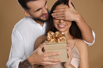 Photo of Man presenting gift to his girlfriend on beige background